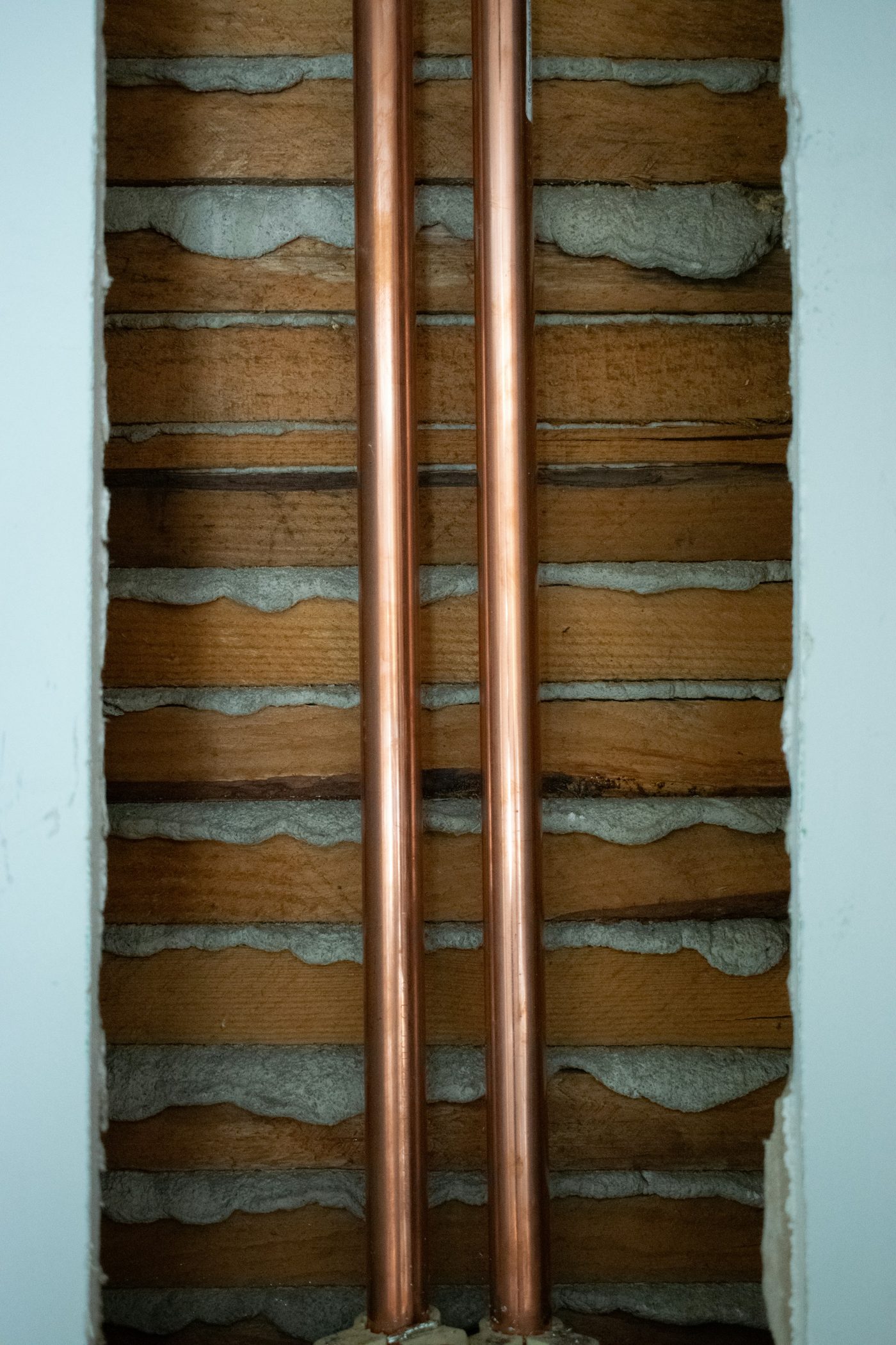 Nieuwe koperen waterleidingen in een opengewerkte oude muur
