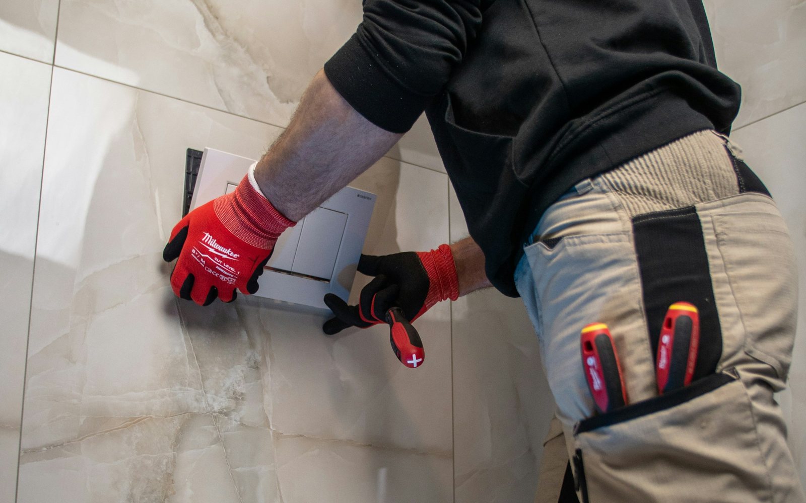 Loodgieter monteert een bedieningspaneel van een inbouwtoilet