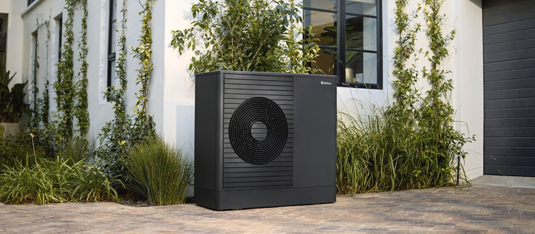 Vaillant aroTHERM plus warmtepomp naast een woning met groene gevelbeplanting